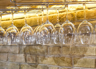 Rows of empty wine glasses on the showcase in the restaurant or bar. Table setting, close up. Glasses for alcohol.
