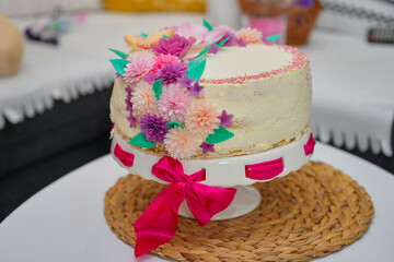 A birthday cake decorated with colored waffle flowers and topped with a colored frosting