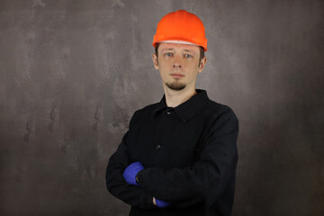 Portrait of a young handsome man worker or engineer in helmet on gray background