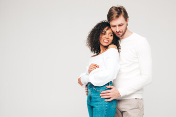 Smiling beautiful woman and her handsome boyfriend. Happy cheerful multiracial family having tender moments on grey background  in studio. Multiethnic models hugging. Embracing each other.Love concept