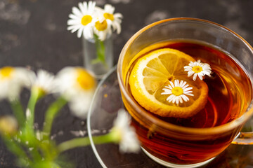 chamomile tea with lemon in a transparent cup on a black background. Breakfast concept, herbal tea.