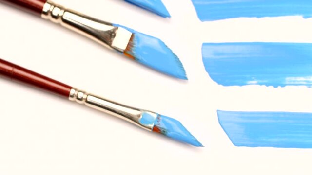 Set of brushes with watercolor for drawing in different shapes. Thick and thin brushes next to thick and thin lines on canvas or white paper. Drawing concept. Close-up macro shot