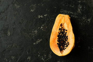 Sliced fresh and tasty papaya on a black textured background. Tropical fruit. Copy space