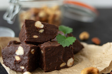 Homemade chocolate fudge garnished with mint leaves and served with tea on a black background. Nuts...