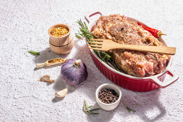 Raw pork roll stuffed with garlic and carrots in a ceramic roasting dish