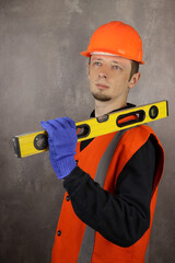 Portrait of a male engineer or builder with a construction level in hand. Vertical orientation