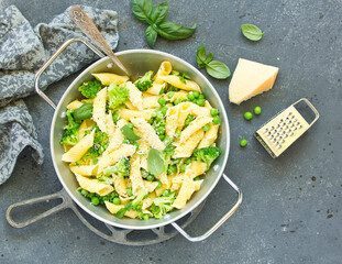 penne pasta with spinach pesto sauce, green peas and broccoli, top view