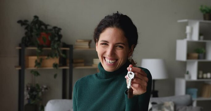 Emotional sincere laughing happy young woman looking at camera, showing keys, celebrating purchasing first dwelling, moving into own house. Real estate services, bank mortgage last payment concept.