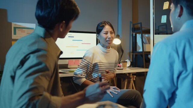 Asia businesspeople stand behind transparent glass wall listen manager pointing progress work and brainstorm meeting and worker post sticky note in office night. Business inspiration, share ideas.