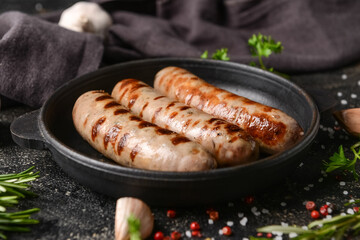 Frying pan with delicious grilled sausages on dark background, closeup
