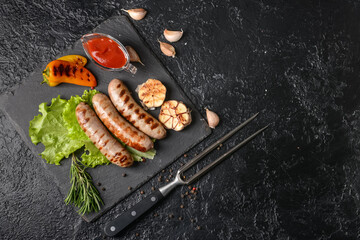 Slate plate with delicious grilled sausages on dark background