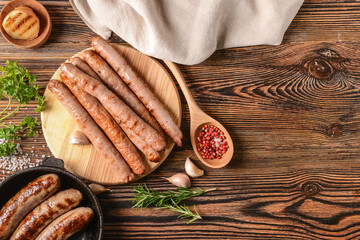 Board with delicious grilled sausages on wooden background