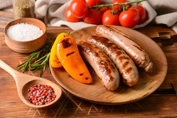 Plate with delicious grilled sausages on wooden background