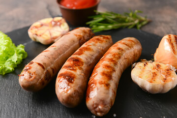 Slate plate with delicious grilled sausages on grunge background