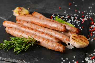 Delicious grilled sausages on dark background