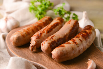 Board with delicious grilled sausages on wooden background, closeup