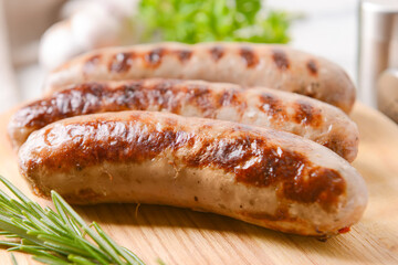Board with delicious grilled sausages on light background, closeup