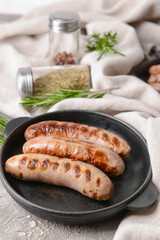 Frying pan with delicious grilled sausages on grey background