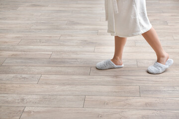 Woman in slippers walking on new laminate flooring at home