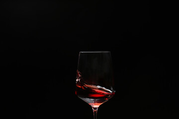 Glass of wine with splash on dark background, closeup