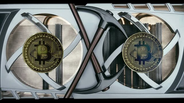 Cooling fans are spinning on the video card, Bitcoin coins shine in the light and two pickaxes as a symbol of cryptocurrency mining using computer video cards. Macro. Closeup