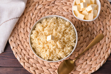 Bowls with tasty couscous and butter on wooden background