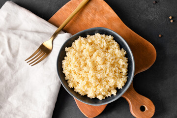 Bowl with tasty couscous on dark background