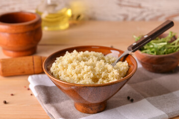 Bowl with tasty couscous on wooden background
