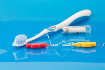 Dental hygiene concept. Tooth brush, interdental brushes and dental floss for avoidance of dental plaque on blue background