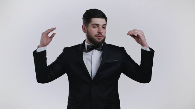 Handsome bored man in tuxedo showing bla-bla-bla gesture with hands isolated on white background. Empty promises, blah concept. Lier