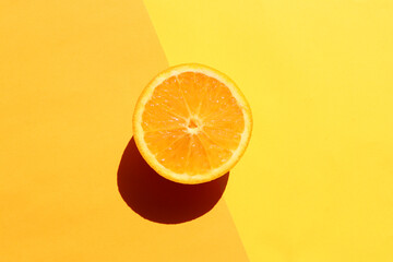 Half of orange on yellow background. Citrus fruit slice on colored backdrop. Top view, copy space....