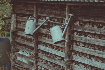 two watering cans hang on the fence