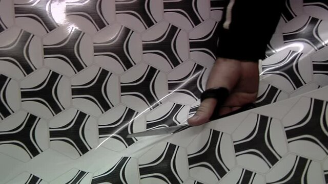 Worker cutting Synthetic Leather Sheet with Hexagons in a Soccer Ball Factory. Close Up.