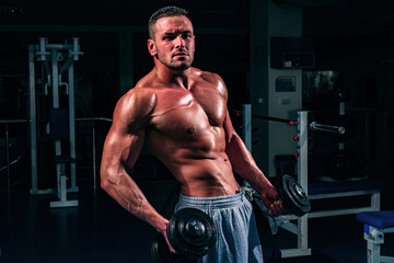 Fototapeta na wymiar Athletic man bodybuilder doing exercises with dumbbell. Fitness muscular body. Gym training.