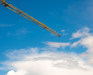 Orange crane boom over blue sky clouds © Gabdulvachit