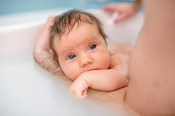 small child takes a bath. Parents bathe the baby. Pretty Baby. The newborn is bathed. Crusts on the baby's face. Bathroom with milk. The newborn is smiling. Beautiful kid portrait. little child smiles