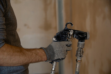 The master paints the walls. A machine for painting walls in the hands of a painter