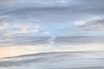 Obraz premium Streaky pastel clouds in early evening, shades of blue, gray, and white, as a nature background 