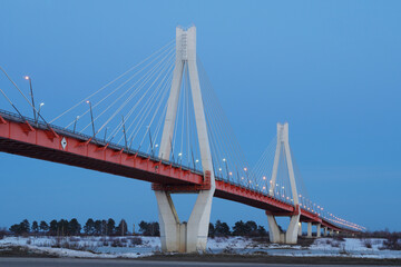 Cable-stayed bridge over the river. Winter, late evening.