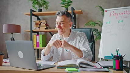 Happy remote work. Cheerful mature teacher video chatting with students online via laptop, laughing and joking