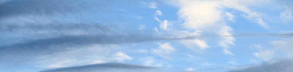 Streaky pastel clouds in early evening, shades of blue, gray, and white, as a nature background
