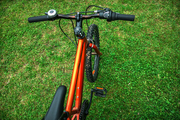 Fototapeta na wymiar A teenage orange bicycle on the green grass in a field