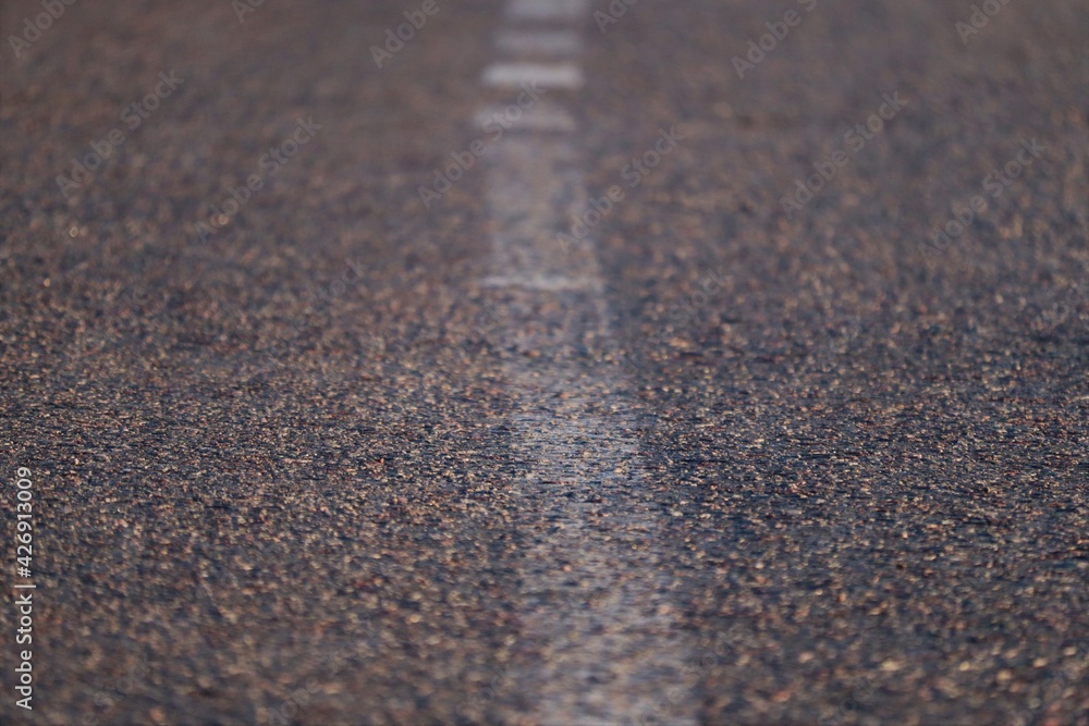 Poster asphalt with a white line in the middle close-up.