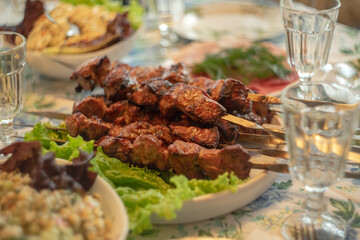 Meat fried shish kebab on the table next to green lettuce leaves