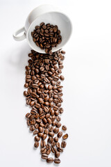 Spilled out coffee beans from white cup