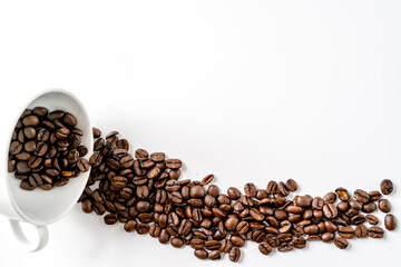 Spilled out coffee beans from white cup