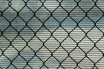 Fence made of metal mesh and plastic fabric.