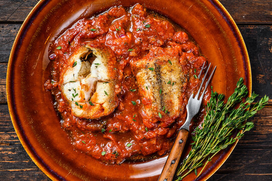 Roast Hake White Fish Fillet With Tomato Sauce In A Plate. Dark Background. Top View