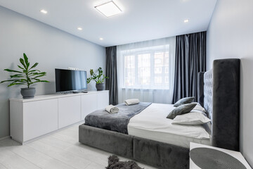 Interior photography, bedroom, in a small studio apartment, with a large bed and white walls