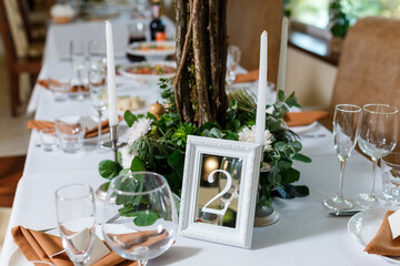 Newlyweds table setting decorated in rustic style. Wedding decor with flowers, candles, succulents, greenery and wooden elements. Nature theme in decoration